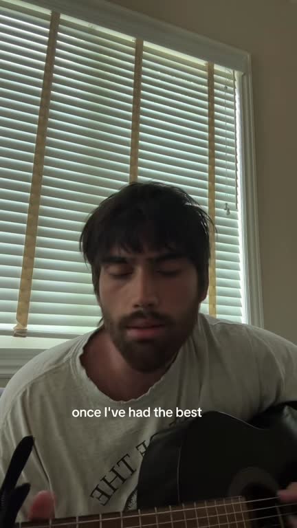 Daniel singing by a window with his guitar